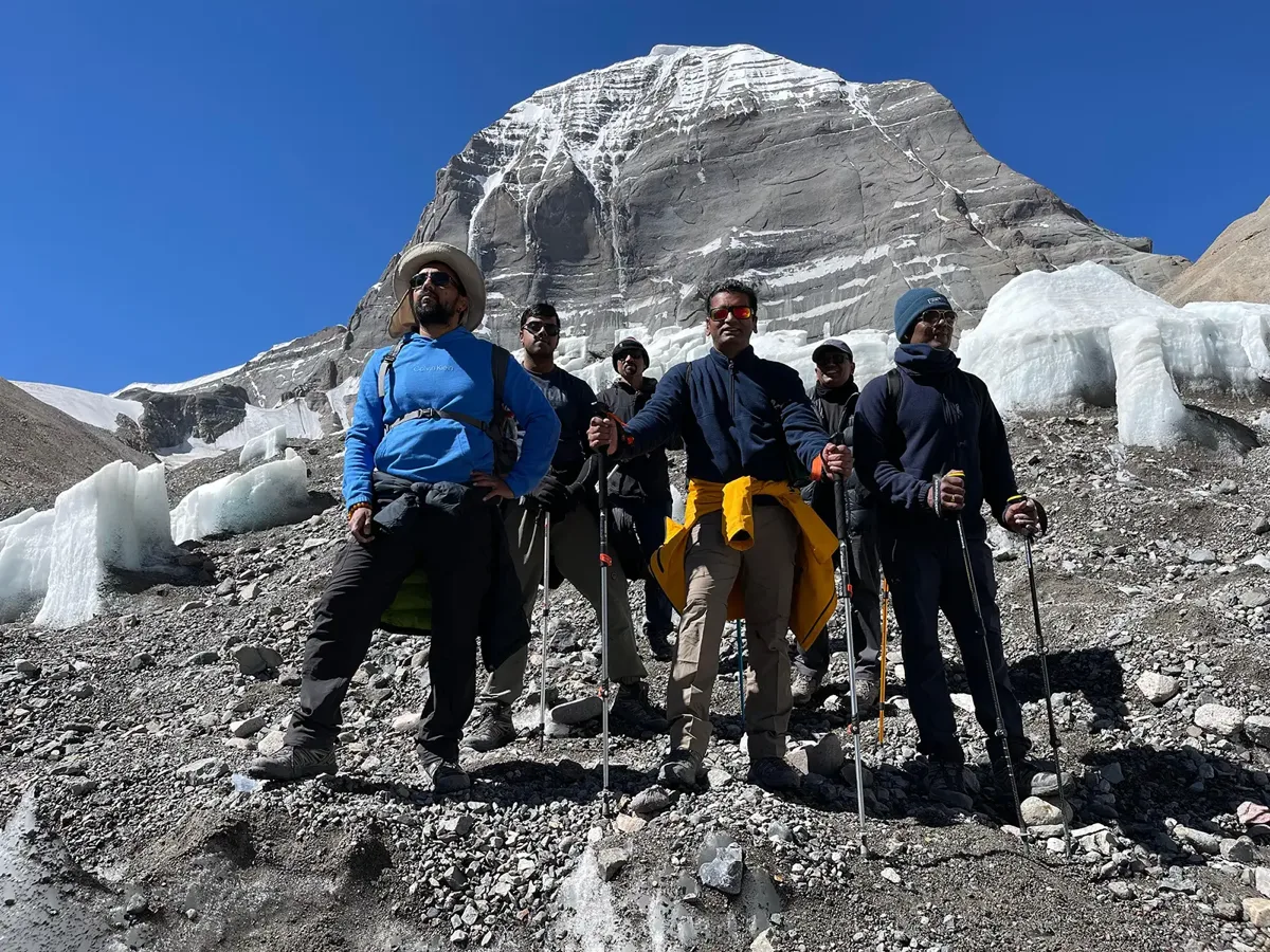 Pilgrims with trekking poles standing below the north face of Mount Kailash